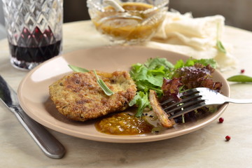 Fried pork chop with fresh herbs and fruit sauce