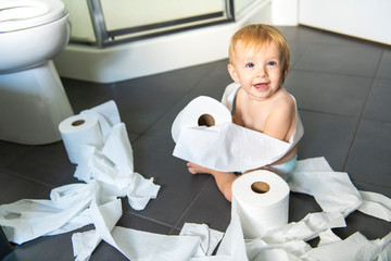 Toddler ripping up toilet paper in bathroom