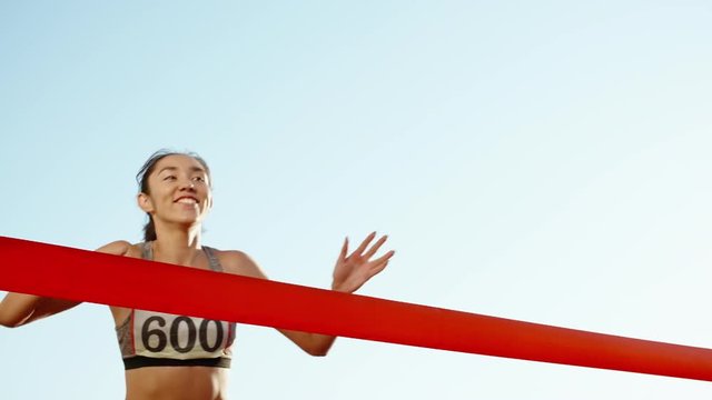 Female athlete on track. Young asian runner runing on track of stadium, happily crossing the red finish line, getting ready for competition