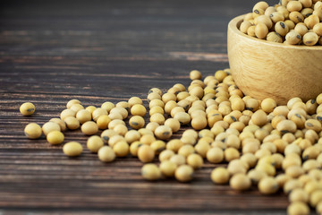 Closeup soy beans in a wooden bowl and on the old dark wooden floor with selective focus and copy space for text, cooking ingredients, healthy eating