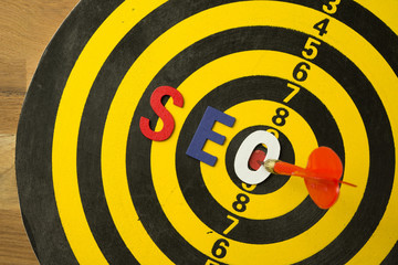 SEO Search Engine Optimization multi color logo alphabets ranking concept on dartboard background with red arrow hit center of target, SEO is one of online marketing business strategy to promote web