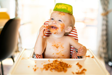 Little baby eating spaghetti dinner and making a mess