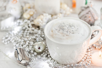 White cup of hot cappuccino coffee on holiday white and silver background, Christmas concept