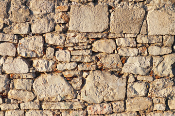 Ancient medieval stone masonry. Texture of a fragment of a wall of an old structure. A background for design and creative work. Decoration and exterior decoration of the building. Construction works.