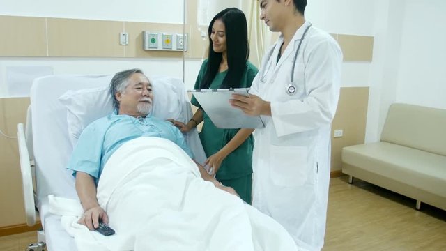 Doctor and nurse visit old man at hospital room. Medical and Health care concept.