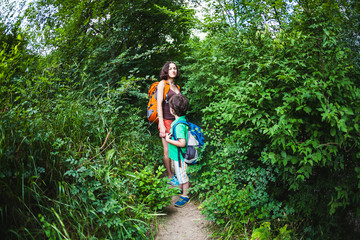 Naklejka na ściany i meble A woman and her child walk along a forest trail.