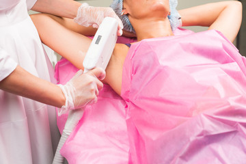 Spa, people and cosmetology concept - Woman having underarm laser hair removal epilation.