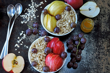 Fototapeta na wymiar Oatmeal with honey and fruit. Porridge in bowls with apple, pear, honey and grapes. Healthy and beautiful breakfast. The concept of dietary nutrition. Superfoods