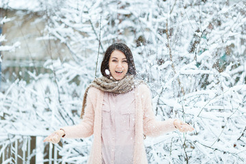 Fototapeta na wymiar cute girl plays with falling snow in the winter forest