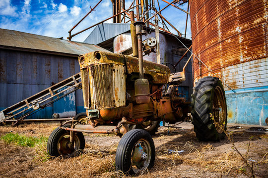 Old abandoned tractor next to the sheet metal sheds
