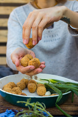 Chickpea falafel balls baked in oven on  cast iron frying pan. Woman hands takes and holds falafel balls served with green fresh onion sprouts for lunch. Vegan, vegetarian healthy food