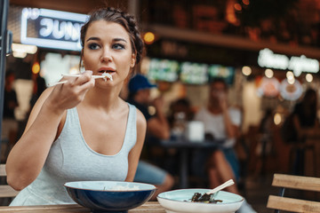 Beautiful woman eating chicken with rice in street cafe of chinese food.