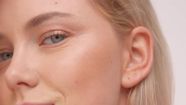 closeup of green eyes of nordic model with blonde hair. Ideal skin, strobbing shiny skin, millennial model, studio, blowing hair