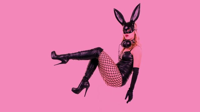 sexy woman dances with large bunny ears mask and black latex body with the legs sawying back and forth