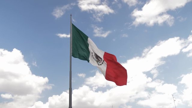 Sharp Mexican Flag Blowing in the Wind in Realtime Located in the Center(Zocalo) of Mexico City with Blue Sky and White Clouds in Background 