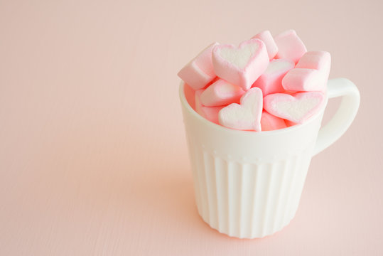 Fluffy pink heart marshmallow in vintage cup on pink background