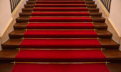 Wooden staircase covered with red carpet background
