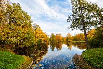 Autumn landscape. Beautiful lake and trees with yellow, green and red leaves. Colorful forest in fall season.
