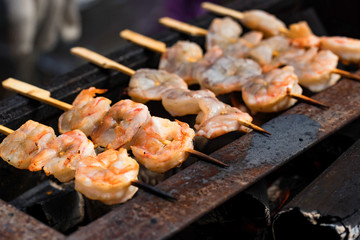 Grilled fried prawns on skewers on metal grid