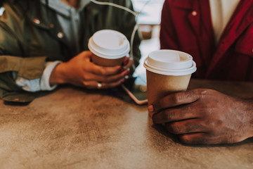 Tasty coffee. Close up of the hands of young people holding cups of hot coffee
