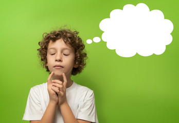 Cute pensive child with empty thought bubble for text, isolated on a vibrant green screen background, concept for ideas education and creativity.