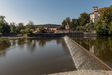 Fototapeta na wymiar sun-lit weirs on the river Sazava in the background of the Sázava monastery building