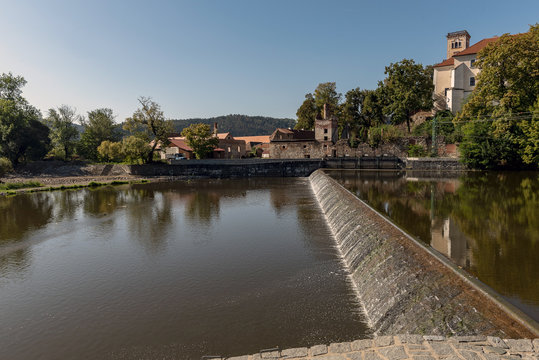 sun-lit weirs on the river Sazava in the background of the S&aacute;zava monastery building
