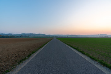 Sonnenuntergang mit Acker und Landstraße