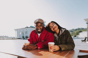 Happy people. Emotional man sitting at the table and smiling while positive girlfriend leaning head to him