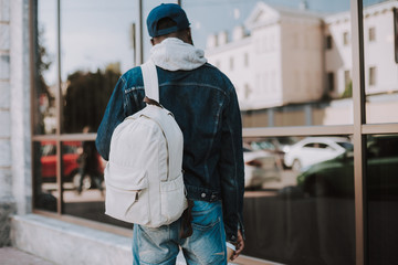 Rear view of a n afro american backpacker having a walk while enjoying urban settin
