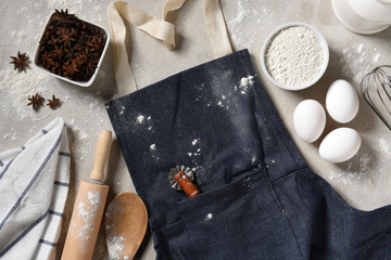 A denim apron with eggs, flour and equipment for making holiday cookies and desserts