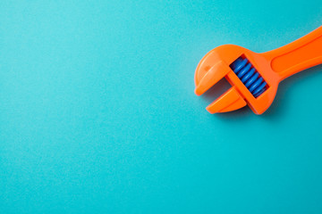 Flat lay of orange adjustable wrench plastic toy on blue background with copy space. Playing with...