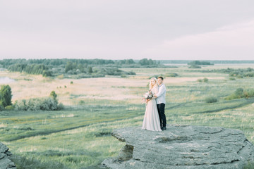 Wedding couple on a walk, photo shoot in the mountains. Fine art style in the decor. A stylish young model