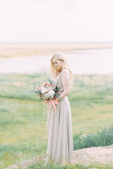 Bride in nature, in the mountains. Wedding in the style of fine art. The mountains and the sunset in the boudoir dress.