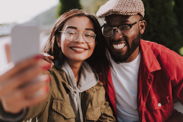 Positive beautiful woman making selfies with his afro American boyfriend while enjoying time together