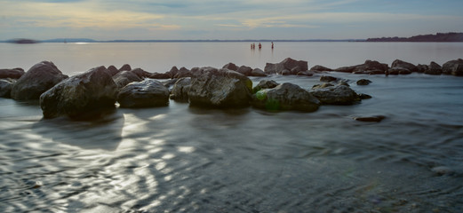 Kiesstrand mit Felsen am See