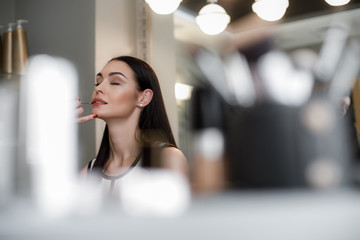 Perfect appearance. Makeup artist appliering classic version of bright red lipstick