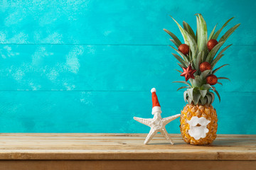 Christmas holiday concept with  pineapple as alternative Christmas tree and starfish on wooden...