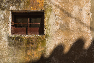 Small window with a grating and enlightened wall