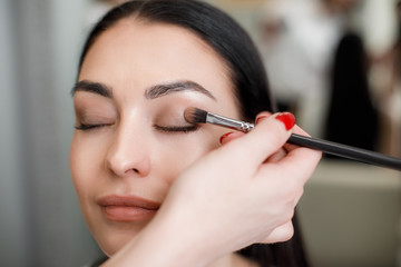 Makeup artist applying shadows to external corners of eyes with special eyeshadow brush