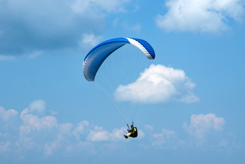 One paraglider flying in the blue sky against the background of clouds. Paragliding in the sky on a sunny day.	