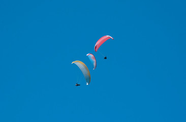 Three paragliders flying in the blue sky against the background of clouds. Paragliding in the sky...