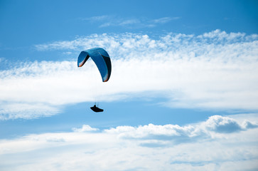 One paraglider flying in the blue sky against the background of clouds. Paragliding in the sky on a sunny day.	