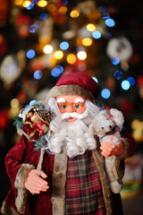 Santa Claus toy with gifts on bokeh background of Christmas tree