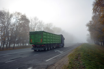 Truck is driving along the road in the morning in a thick fog