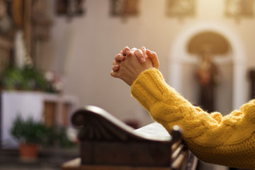 Christian woman is praying with hands crossed in church