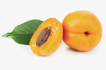 ripe juicy yellow apricots with leaves on a white table