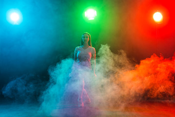 Cheerleading young woman dancing on colourful dark background © satura_