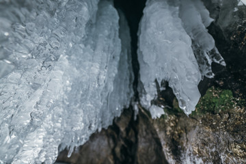 Winter Baikal. Olkhon Island. Ice grotto. Thick blue ice and icicles on the coastal rocks of Olkhon...