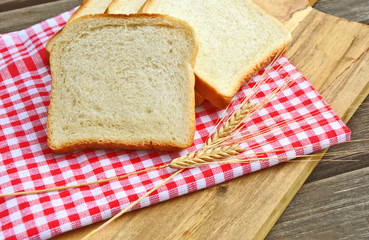 White bread toast with Wheat and red tablecloth on wooden background.